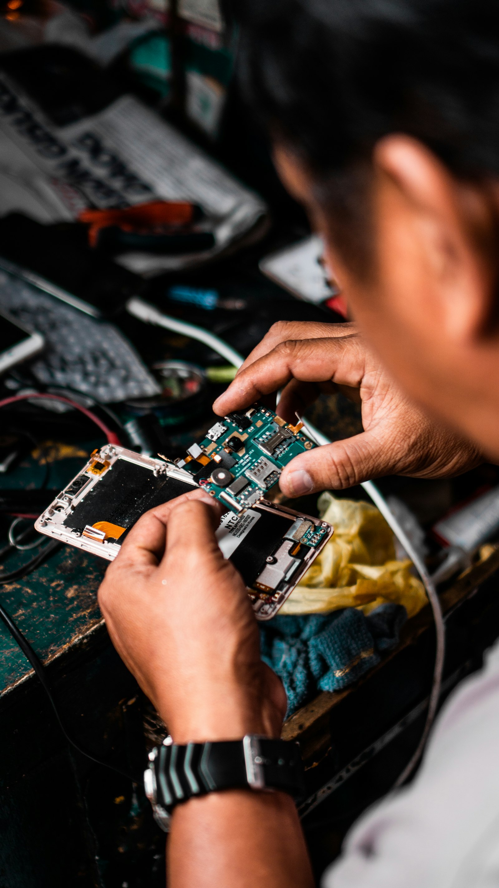 Tehnician reparând placa unui telefon (imagine ilustrativă)